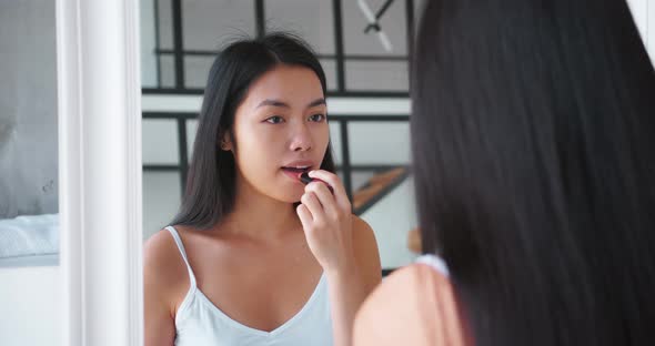 Portrait of Beautiful Cheerful Longhaired Brunette Asian Woman Applying Hygienic Balm on Lips