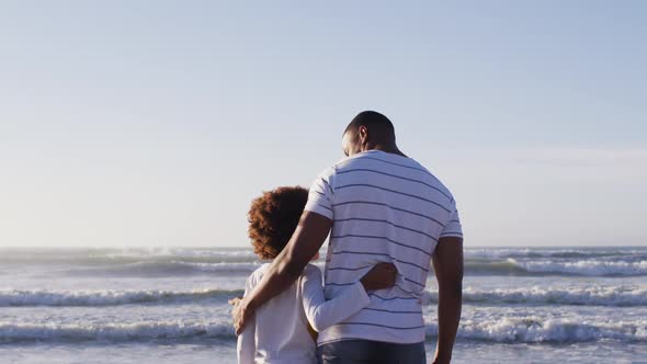 Rear view of african american father and son enjoying the view while standing the beach