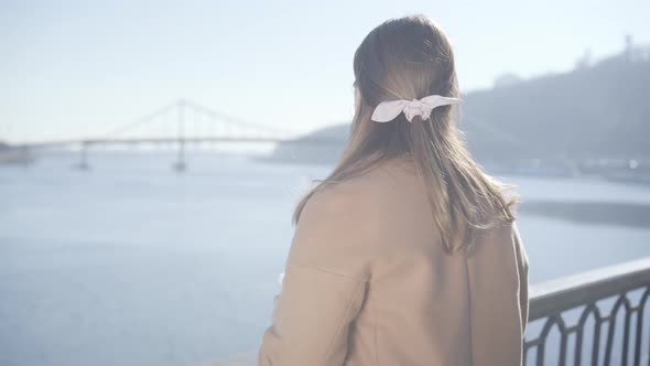 Back View of Young Caucasian Woman Looking at River From Bridge on Sunny Autumn Day. Positive