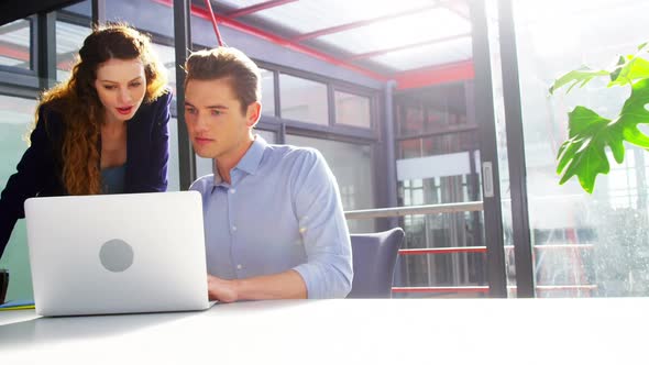 Business executives discussing over laptop