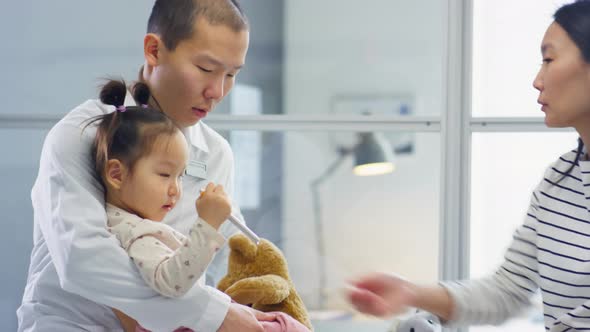 Asian Pediatrician Playing with Child and Talking with Mother