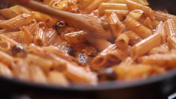 Stirring Pasta in Frying Pan with Wooden Spoon