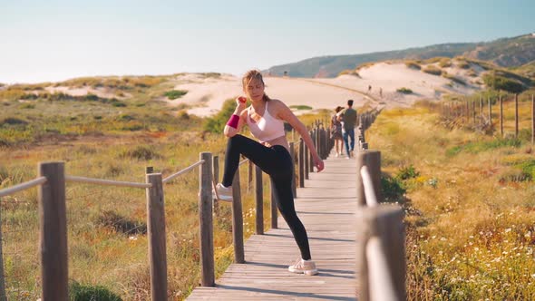 Flexible Caucasian Girl Stretches Legs After an Intensive Running Workout