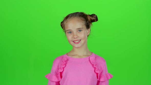 Baby Smiles and Looks Into the Distance, Covering Her Face with Her Hands. Green Screen