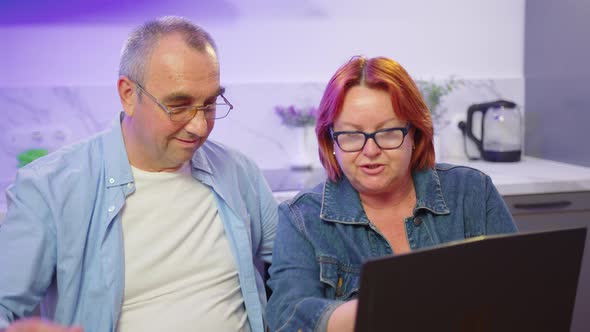 Happy Old Middle Aged Couple Using Laptop Talking Together Doing Online Shopping Senior Mature