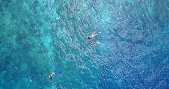 Wide angle above travel shot of a white sandy paradise beach and aqua blue water background