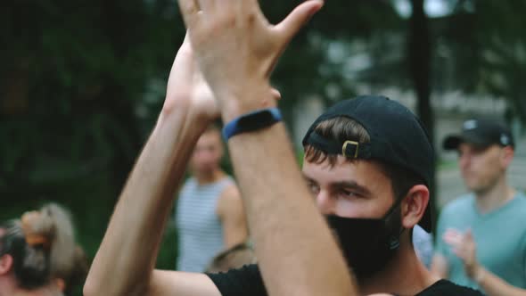 Masked Male Person Claps Hands on Political Opposition Rally Under Lockdown Rule