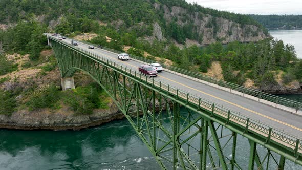 Cars driving over the green steel bridge at Deception Pass State Park.
