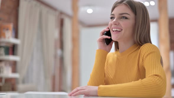 Happy Creative Young Woman Talking on Smartphone in Office