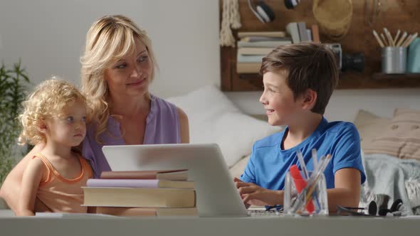 Happy family at home, mother with son and daughter have fun using computer