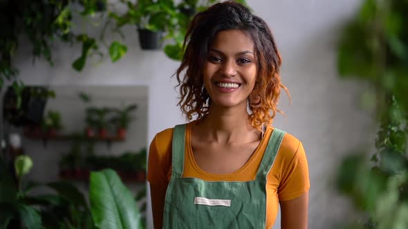 African Woman in Apron Smile Against Background of Plant Spbd