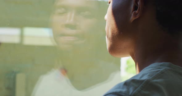 African american man looking at the window and drinking coffee at home