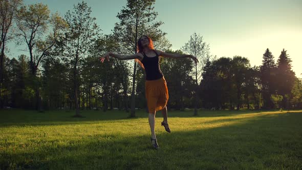 Attractive Female in Long Red Skirt Jumping and Dancing Outdoor in a Park