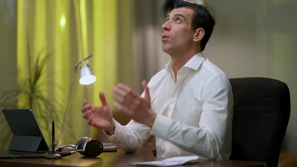 Overwhelmed Middle Eastern Man Sighing Looking Up and Meditating Sitting at Table in Home Office