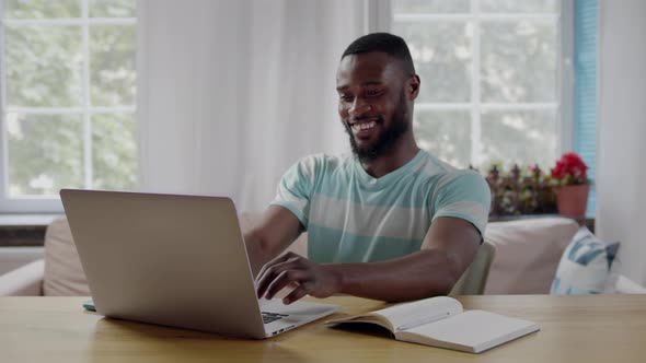 Happy AfricanAmerican Ethnicity Man Raising Fist Celebrating Success Using Laptop at Home