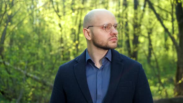 A Bald Intelligent Ecologist Man with a Beard and Glasses Looks at the Camera