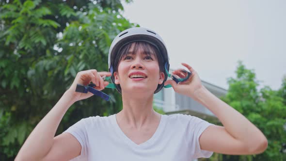 Asian sportswoman wear protective sport helmet before ride Surf Skate Board to exercise on street.