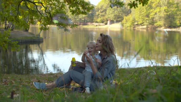 Happy mother and her son blowing soap bubbles