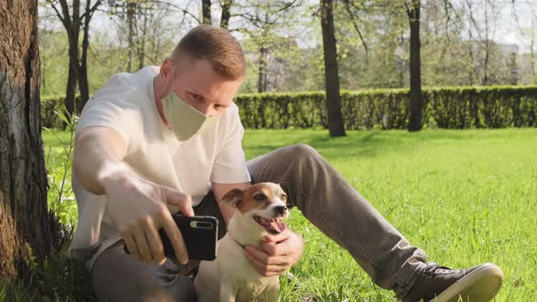 Man in Face Mask Taking Selfie with Cute Dog in Park