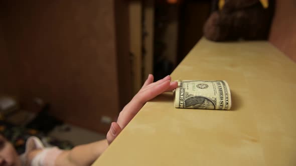 The woman places the dollars on the top shelf in a hard-to-reach place
