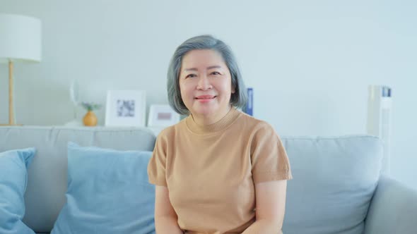 Portrait of Senior woman smile and look at camera in living room at home enjoy retirement life.