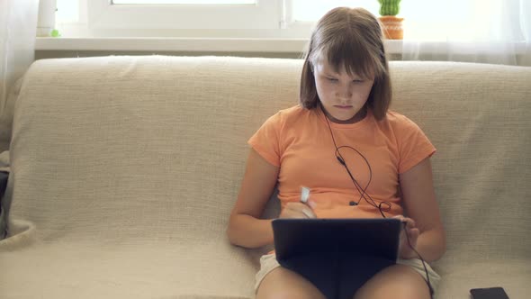Teen Girl At Home On Couch Working In Tablet