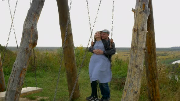 Romantic Couple Hugging Swinging on a Swing in the Park Woman and Man