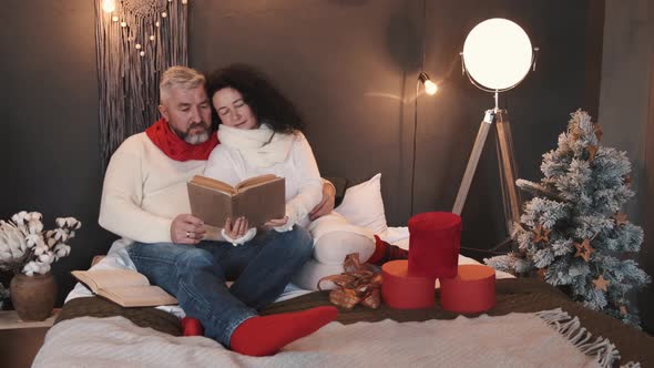 Senior Couple Reading and Relaxing on the Bed in Christmas Atmosphere