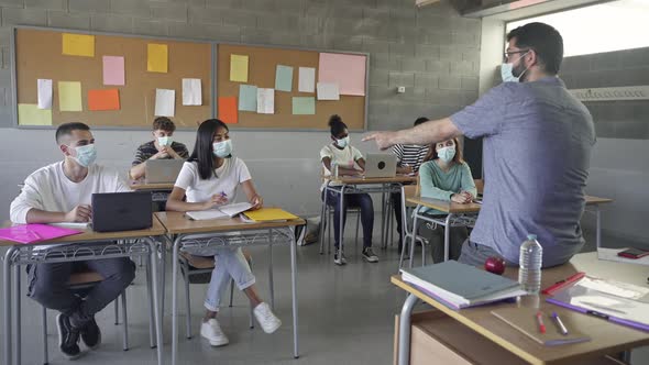 Secondary School Students and Teacher Wearing Medical Face Masks Writing Notes During Class at the