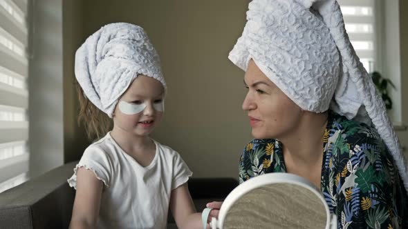 Beautiful Mother in Bathrobe and Her Little Daughter Together with Towels on Head and Mask on Face