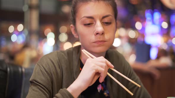 Young Woman Eating Asian Food with Chopsticks. New Food Experience While Traveling. 