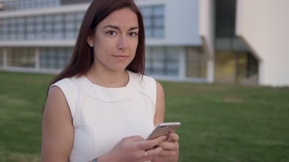 Lovely Redhead Woman Using Smartphone and Looking at Camera