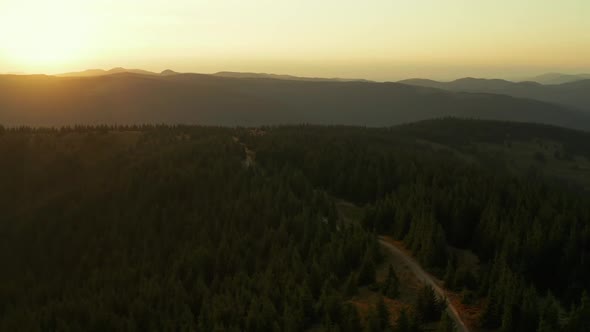 Aerial Mountain Sunrise View Against Golden Morning Sky Green Trees Road Scene