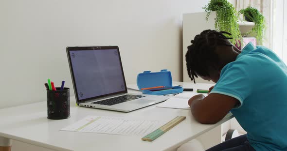 African american boy doing homework looking at laptop with copy space at home