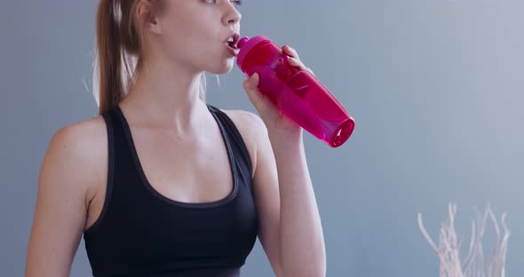 Woman Drinking Water From Bottle After Working Out at Home