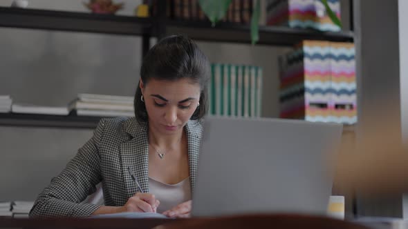 Woman Working From Home Using Laptop Computer While Reading Text Message