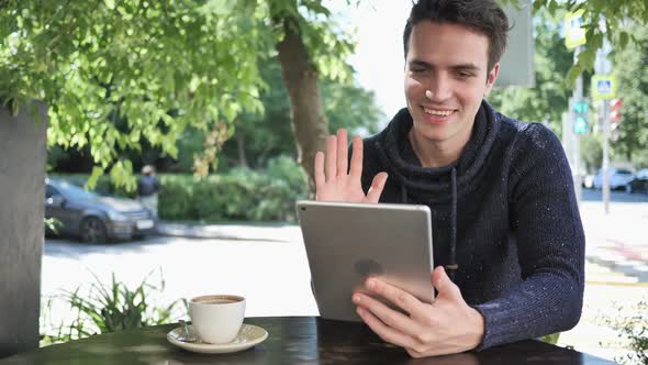 Online Video Chat on Tablet By Man Sitting in Cafe Terrace