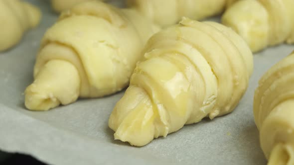 Close Up Spreading of Egg Yolk on Italian or French Croissants with Silicone Brush Laying on Bakery