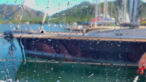 Close Up View Through Wet Glass of the Crew of a Huge Boat Washes a Sailing Yacht in Clear Sunny