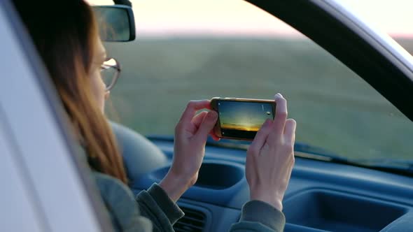 Girl in Glasses Taking Photo of Sunset From Car