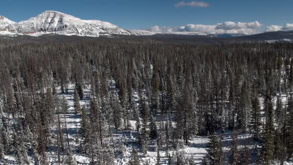 Flying backwards over snow covered landscape passing frozen lake