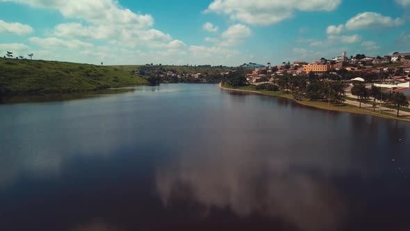 Incredible aerial flying over a beautiful blue lake next to a small village on a sunny day