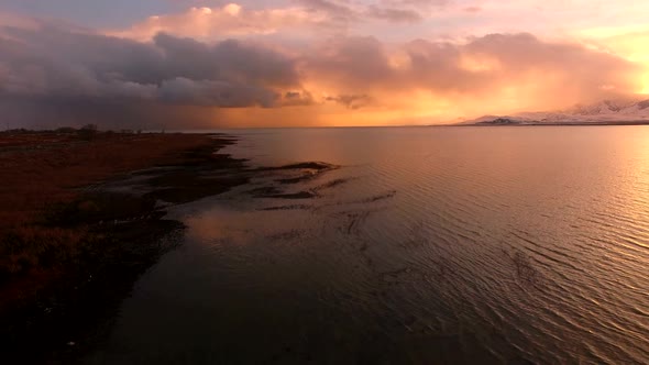 Flying backwards over shoreline during colorful sunset