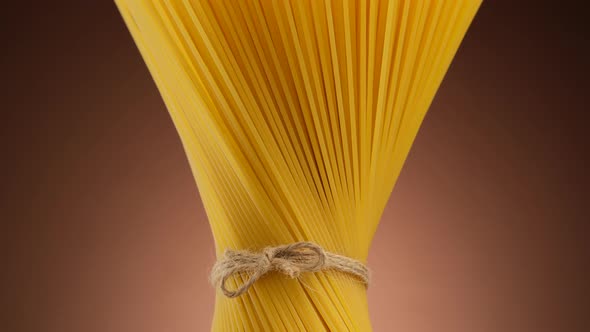 Authentic Italian spaghetti pasta on brown background, rotate. Vegan, vegetarian food