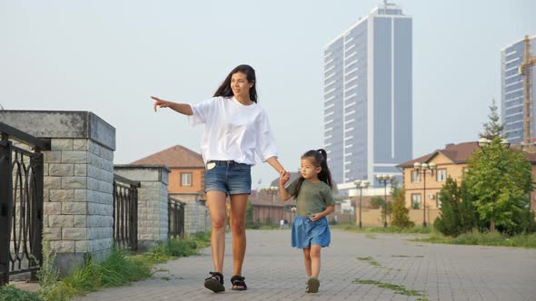 Mother Walks with Korean Little Girl Along Embankment