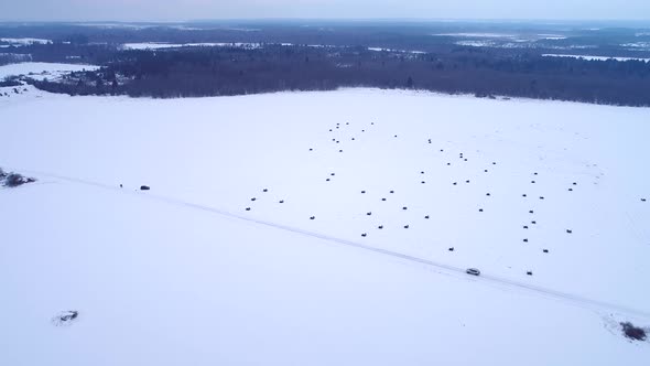 Aerial view of a car driving on a snowy road in the blizzard on Vormsi island, Estonia.