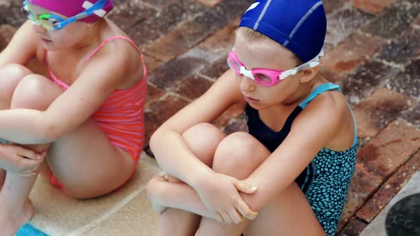 Cute little kids sitting near swimming pool