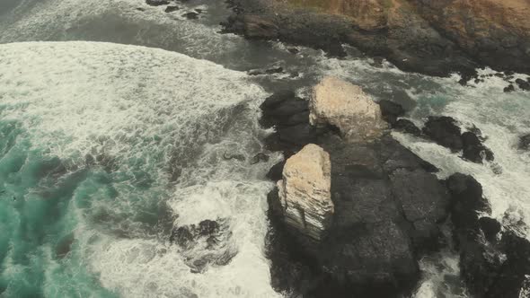 Aerial Reveal of rocky formations among the waves in a cloudy day at Pichilemu, Chile-4K