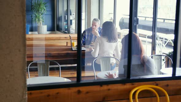 Business people discussing over laptop in cafeteria at office 4k