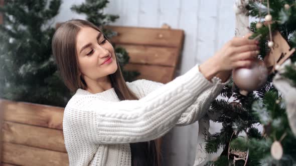 Attractive Woman Hanging Toy Ball on Christmas Tree